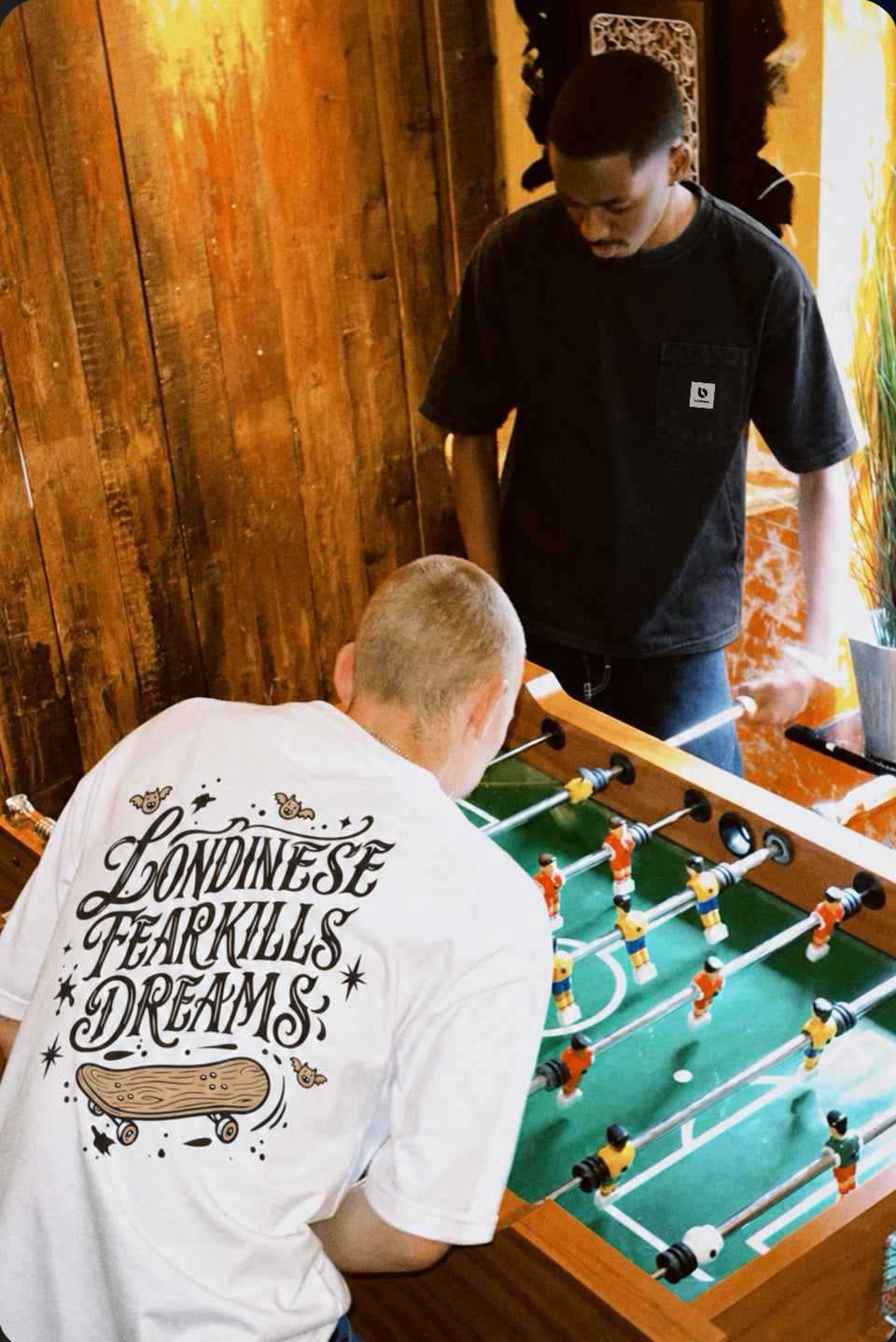Due ragazzi con t-shirt Londinese che giocano a calcio balilla